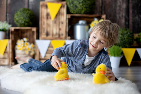 Cute young preschool child, boy, playing with ducks at home, beautiful spring decoration for birthday behind himの写真素材