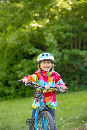 Happy kid boy, having fun in park with a bicycle on beautiful day. Active childの写真素材
