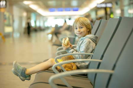 Children, boy brothers, traveling for summer holiday, waiting at the airport to board the aircraftの写真素材