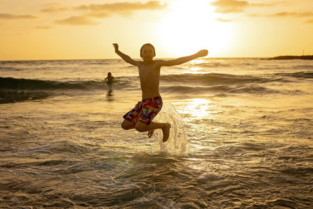Happy teenager boys, running and playing on the beach on sunset, splashing water and jumping on the sand. Tel Aviv, Israelの写真素材