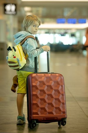 Children, boy brothers, traveling for summer holiday, waiting at the airport to board the aircraftの写真素材