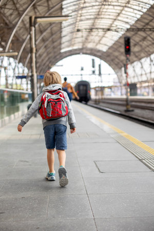 Cute preschool child with backpack, running for the train on a trainstation, summertimeの写真素材