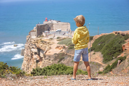 Family with children, visiting the beach with the biggest waves in the world in Nazare, Portugal, summertimeの写真素材