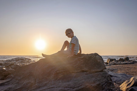 Happy children, enjoying sunset over the ocean with their family, rocky beach in Portugalの写真素材