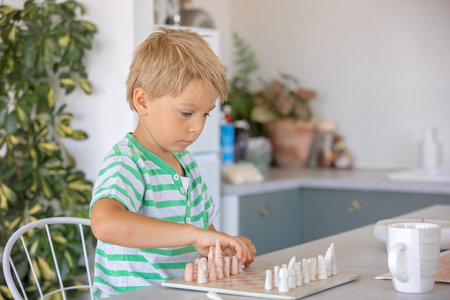 Boys, siblings, playing chess game at home, children enjoying board games togetherの写真素材