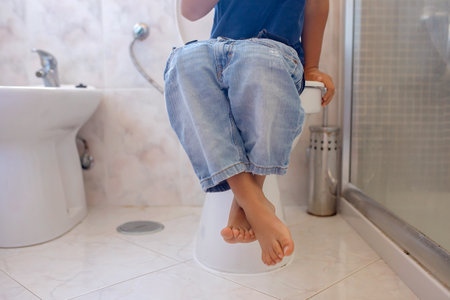 Cute child, boy, sitting on the toilet in bathroomの写真素材