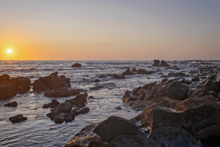 Happy children, enjoying sunset over the ocean with their family, rocky beach in Portugalの写真素材