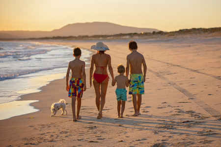 Happy children, boys, playing on the beach on sunset, kid cover in sand, smiling, laughing, enjoying some funの写真素材
