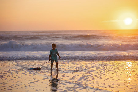 Happy children, boys, playing on the beach on sunset, kid cover in sand, smiling, laughing, enjoying some funの写真素材
