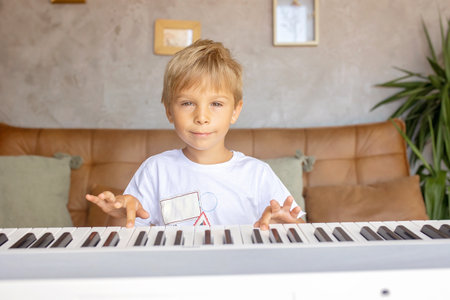 Child, blond boy, playing piano at home, learningの写真素材