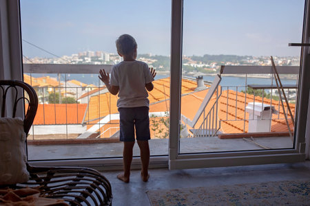 Blond child, boy, sitting on the couch at home,cuddled in blanket, enjoyingの写真素材