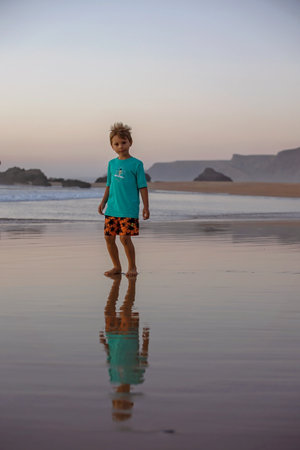Happy children, boys, playing on the beach on sunset, kid cover in sand, smiling, laughing, enjoying...