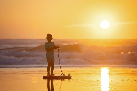 Happy children, boys, playing on the beach on sunset, kid cover in sand, smiling, laughing, enjoying...