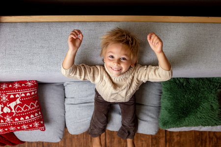 Beautiful blond child, young school boy, playing in a decorated home with knitted toys at Christmasの写真素材