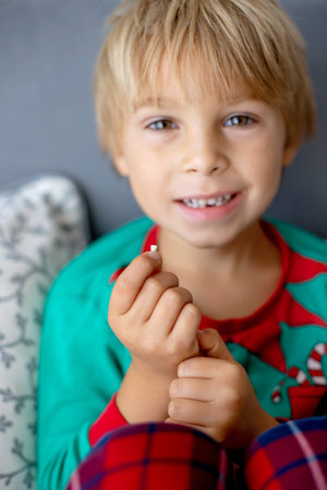 Sweet blond preschool child, boy, loosing his first milk tooth, smiling happily, holding the little...