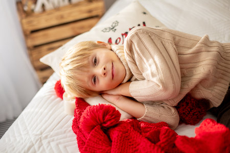 Beautiful blond child, young school boy, playing in a decorated home with knitted toys at Christmasの写真素材