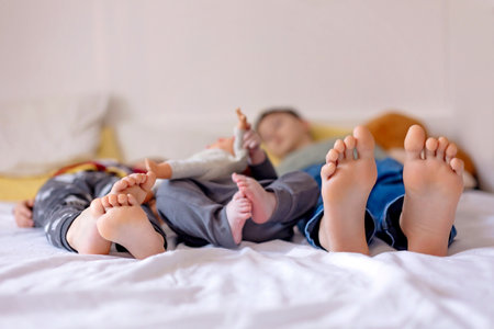 Chlildren feet, little baby boy and older brothers feet, baby lie down in bed in the afternoonの写真素材
