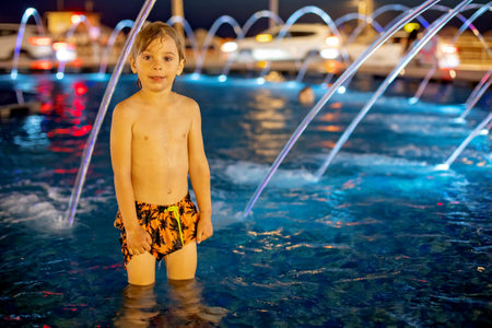 Cute child, boy, playing with water in fountain in Tel Aviv, lights and colorsの写真素材