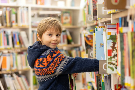 Smart child, school boy, educating himself in a library, borrowing books to readの写真素材