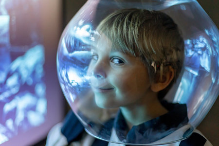 Cute child, boy, dreaming of becoming astronaut and flying into space. reflection of moon in his helmetの写真素材