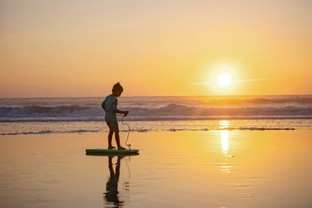 Happy children, boys, playing on the beach on sunset, kid cover in sand, smiling, laughing, enjoying some funの写真素材