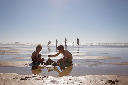 Happy children, boys, playing on the beach on sunset, kid cover in sand, smiling, laughing, enjoying...