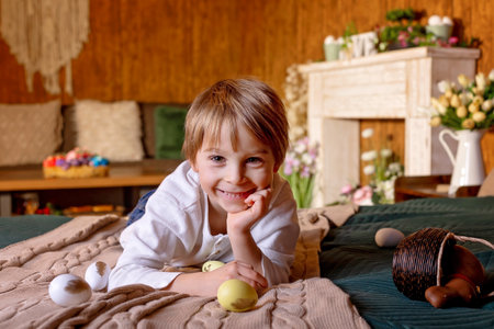 Cute school child, boy, holding basket with easter eggs on easter background, studio shotの写真素材