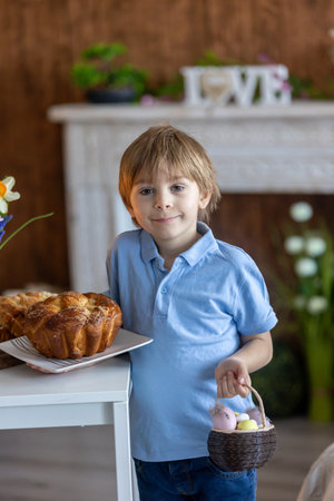 Cute preschool child, boy, holding sweet brioche bun for Easter, traditional swee bread baked with...
