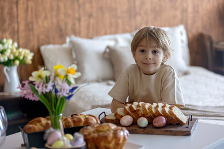 Cute preschool child, boy, holding sweet brioche bun for Easter, traditional swee bread baked with almonds, nuts and sugar, homeの写真素材