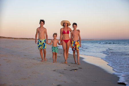 Happy children, boys, playing on the beach on sunset, kid cover in sand, smiling, laughing, enjoying some funの写真素材