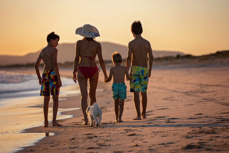 Happy children, boys, playing on the beach on sunset, kid cover in sand, smiling, laughing, enjoying some funの写真素材
