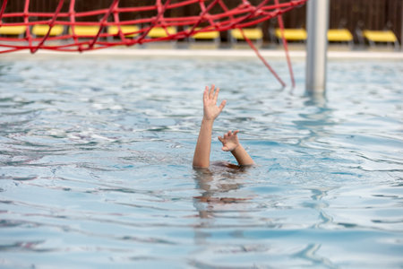 Hands of drowning person stretching out of the water in swimming pool needing help. Stress concept, summertimeの写真素材