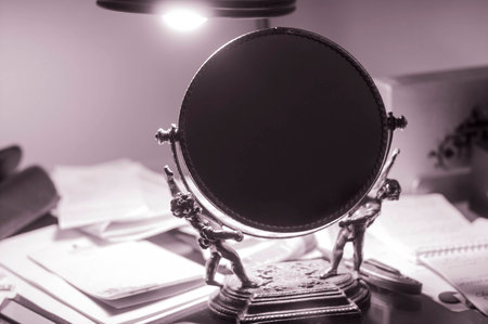 Mirror on messy office desk with light on.の写真素材