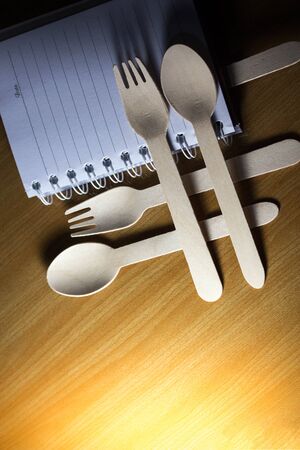 Spoons, forks, made of wood on a wooden background. Blank notebook mock up ,Template for advertising or brandingの写真素材