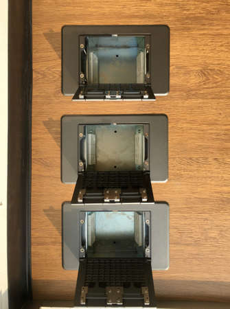 Floor plug,pop up plug in metal cover installed in wooden floor.Electrical work.System engineering.