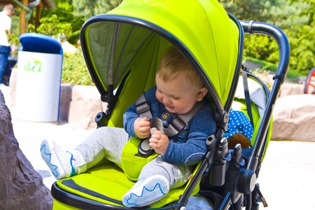 Little boy is sitting in pram with a smiling face and is happy