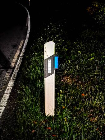 A reflector post at night on an empty country road