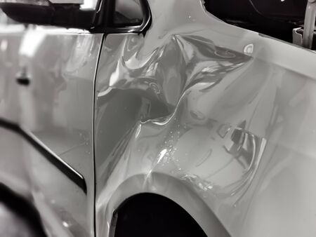 A small dent in the fender of a white metallic carの写真素材