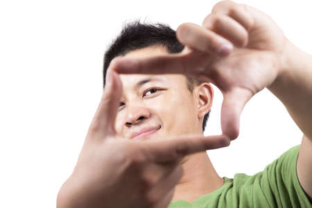 Close-up portrait of young asian man looking through framed handsの写真素材