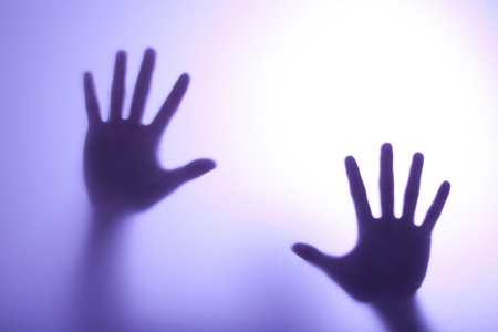 blurry hands reaching out and touching glass with Blue light