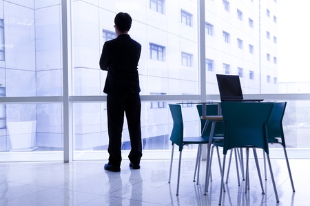 Businessman standing in the  office and laptop on the tableの写真素材