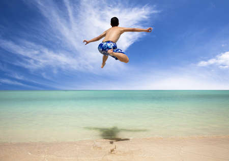 Happy young man jumping on the beach