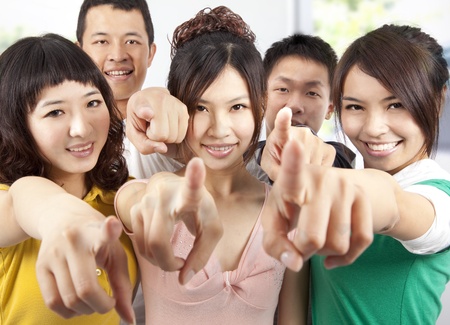Portrait of a smiling asian students pointing at you の写真素材
