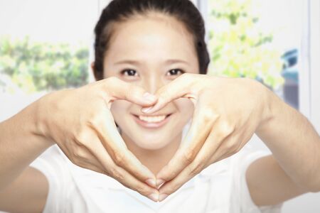 smiling young woman make heart shapeの写真素材