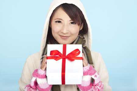 winter portrait of smiling asian woman with a gift 