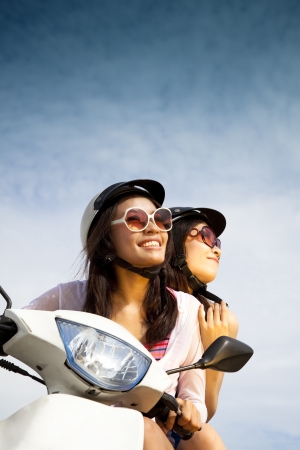young woman riding scooter on the sunny dayの写真素材