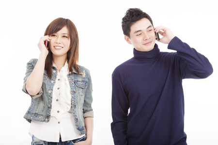 Young couple talking on mobile phone isolated on whiteの写真素材