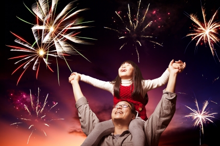 father and daughter looking fireworks in the evening skyの写真素材
