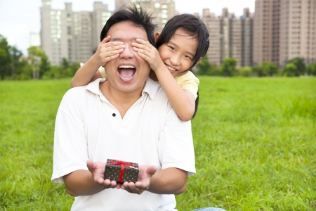 surprised father holding gift box from little girl for father's dayの写真素材