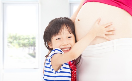 happy  little girl hugging a pregnant motherの写真素材